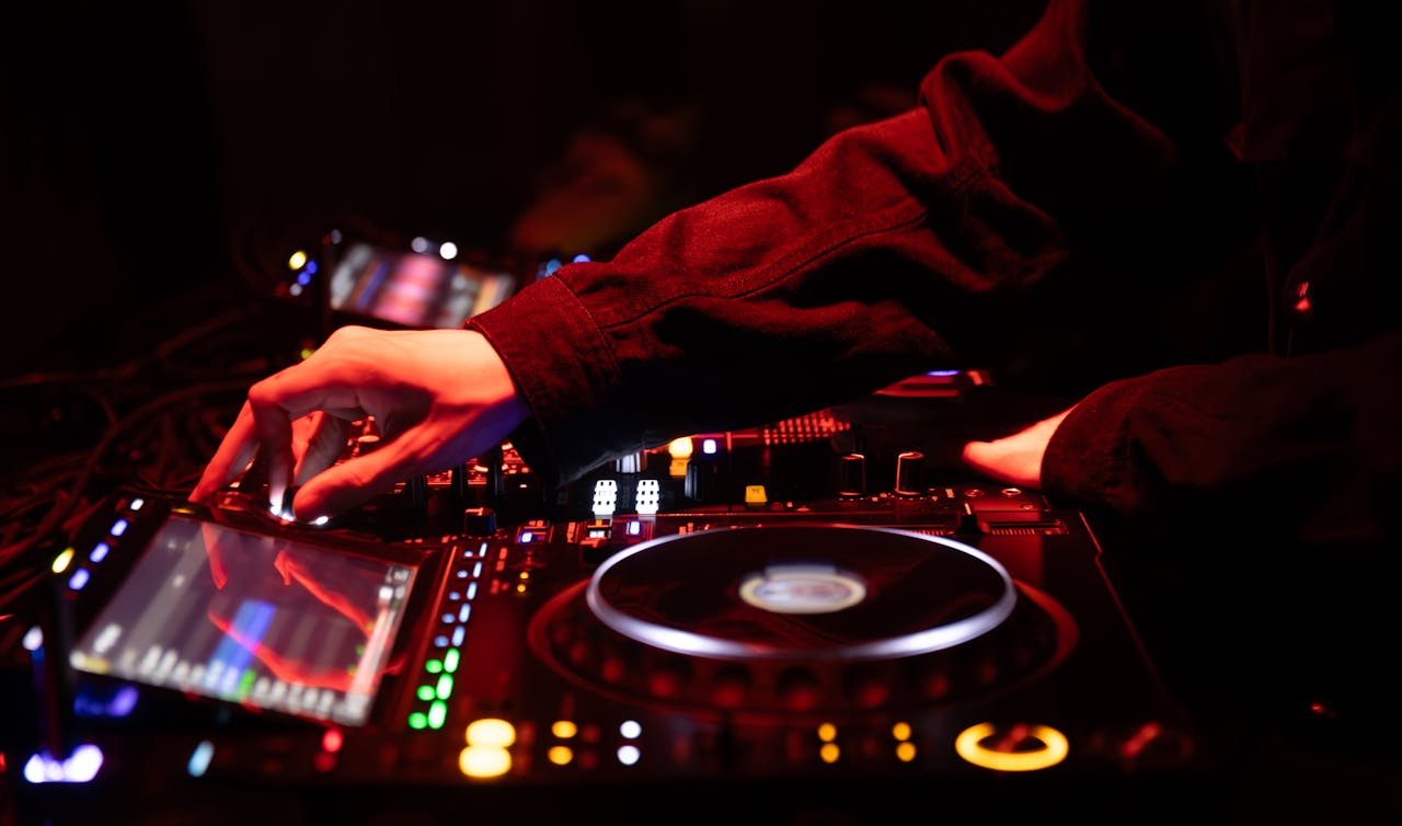 A DJ skillfully adjusting the sound mixer during an energetic concert, creating a vibrant musical experience.